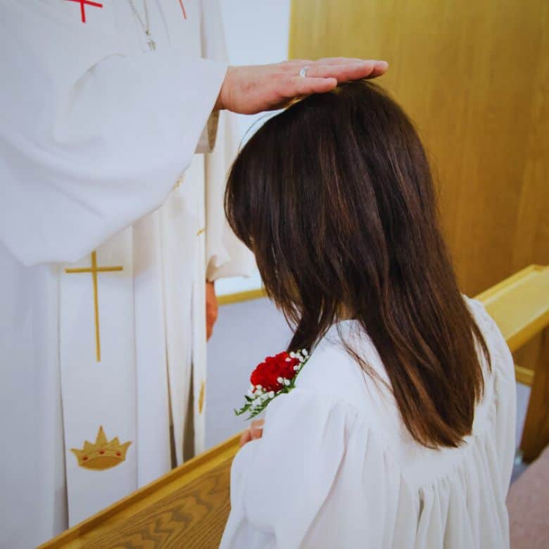 Girl confirmand with pastor's hand on her head